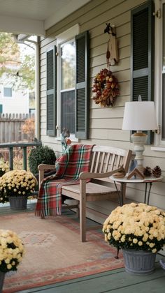 the front porch is decorated for fall with flowers and potted plants on the floor