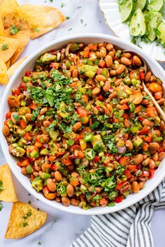 a white bowl filled with bean salad and tortilla chips