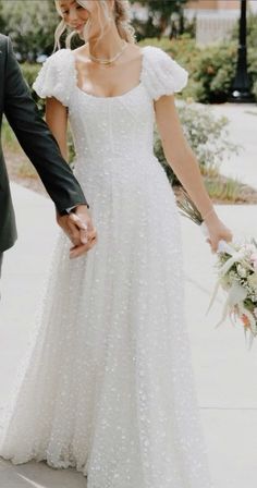 a bride and groom walking down the street holding hands