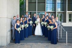 a large group of people in formal wear posing for a photo on the steps outside an office building