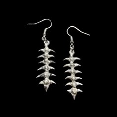 two pairs of silver earrings on black background