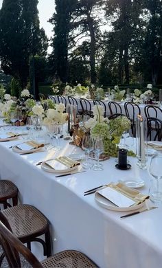 a long table is set with white flowers and place settings