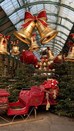 christmas decorations and bells hang from the ceiling in an indoor market area with red chairs