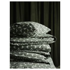 a stack of pillows sitting next to each other on top of a bed covered in black and white sheets