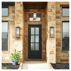 a black front door with two lights on it and a plant in the foreground