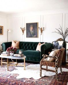 a living room with green couches and paintings on the wall above them, along with an animal print rug