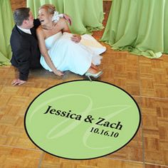 a bride and groom sitting on the floor in front of a green circle with their names