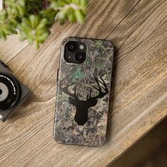 an iphone case with a deer head on it next to a camera and some plants