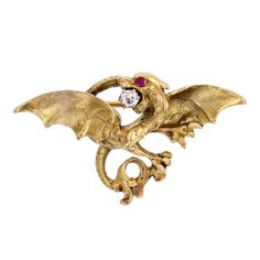 Brooch in 18 karat yellow gold, eagle head hallmark. Magnificent antique brooch depicting a chimera with its wings spread. The creature's mouth is open, and between its fangs is an antique brilliant-cut diamond. Its eye is a small ruby. The clasp is a pin with a safety hook on the back, which is also chased. Total weight of the diamond : 0,08 carat. Height : 2.1 cm approximately, width : 4.1 cm approximately, thickness 6.4 mm approximately. Total weight of the jewel : 9,6 g approximately. Authen Luxury Traditional Gold Brooches, Luxury Unique Yellow Gold Brooch, Gold Eagle, Antique Brooches, Eagle Head, Enamel Brooch, Gold Brooches, Rose Cut Diamond, Natural Pearls