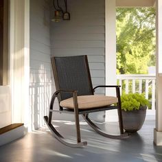 a rocking chair sitting on the porch next to a planter with flowers in it