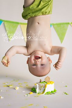 a baby is upside down on his head while playing with a piece of cake in front of him