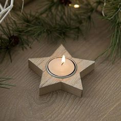 a wooden star shaped candle holder with a lit candle