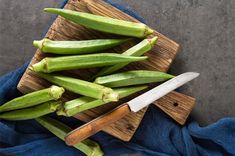 green beans on a cutting board with a knife next to them and a blue towel