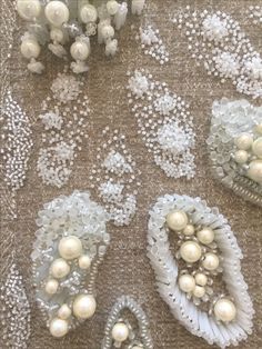 several pieces of white beaded fabric with pearls and beads on them, all in different shapes and sizes