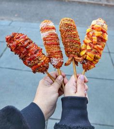 someone is holding up several skewers of food on the street and it looks like they are made out of meat