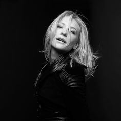 a black and white photo of a woman with blonde hair wearing a leather jacket, posing for the camera