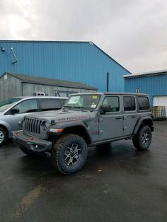 a gray jeep parked in front of a blue building