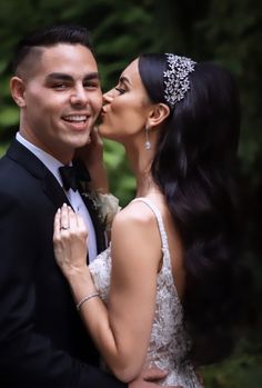 a bride and groom kissing each other in front of trees