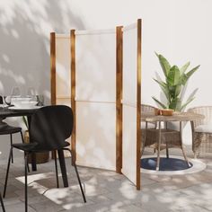 an outdoor dining area with chairs, table and privacy screen in the middle of it