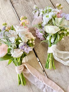 two bouquets of flowers are tied together on the floor with ribbons around them and sitting next to each other