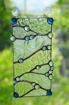 a green and blue glass hanging from a window