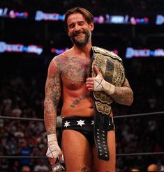 a man with tattoos holding a wrestling belt