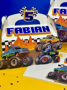 two boxes with monster trucks on them and the number five in front of them, sitting on a yellow surface