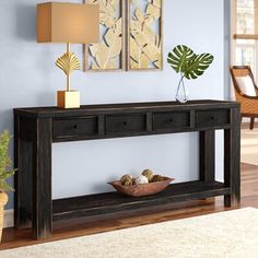 a black console table with two drawers and a bowl on it in front of a blue wall