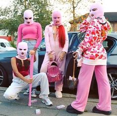 four people in pink costumes standing next to a car with their faces painted like they're talking on the phone