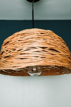 a light that is made out of wicker and hanging from a ceiling lamp fixture