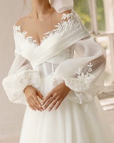 a woman in a white wedding dress is holding her hands on her hips and looking off to the side