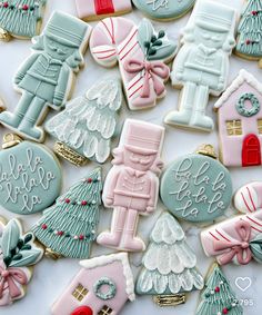 decorated christmas cookies are displayed on a white tablecloth with pink and blue decorations,