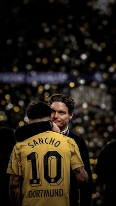 two men standing next to each other in front of a stadium filled with people and confetti