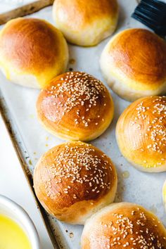 bread rolls with sesame seeds on a baking sheet