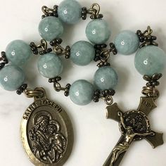 Handmade traditional Catholic single decade tenner rosary using green dyed jade smooth stone round beads. Antique bronze daisy bead caps on every bead with additional flower bead caps on Our Father bead. Antique bronze St. Joseph-Patron Saint of fathers, families and carpenters-Medal with Miraculous Medal Crucifix. Hail Mary beads are 8mm with the Our Father bead being 10mm. Designed to be used and/or displayed. Measures about 10" long. This rosary would make a beautiful gift for a baby shower, Baptism, First Communion, Confirmation, Father's Day, or any other special event or occasion. Comes in a beautiful black velvet pouch. I ship same or next business day. All of my rosaries are one of a kind and are my own personal creation. Photos are a part of the description-you will receive the ex 8mm Jade Beads For Spiritual Use, Spiritual Rosary Bracelet With Polished Beads, Rosary With Natural Stones For Meditation, Turquoise Rosary Bracelet With Round Beads, Spiritual Turquoise Rosary Bracelet With Round Beads, Turquoise Spiritual Rosary Bracelet With Round Beads, Natural Stone Rosary With Round Beads For Meditation, Green 8mm Beads Spiritual Rosary, Green Rosary With 8mm Beads