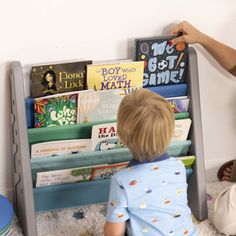 a little boy sitting on the floor in front of a book shelf filled with books