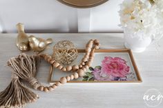 a wooden beaded necklace on a tray next to a flower vase and other items