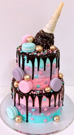 a three tiered cake with chocolate icing and colorful decorations on the top, topped with an ice cream cone