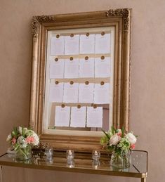 a table with vases and flowers on it in front of a framed calendar display