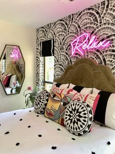 a bed room with a neatly made bed and a neon sign on the wall above it