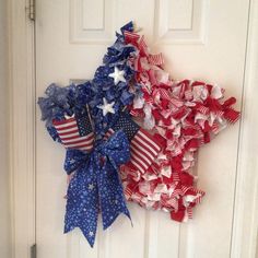 two patriotic wreaths hanging on the front door with stars and ribbons attached to them