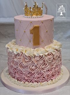 a pink and gold cake with a number one on top, decorated with icing