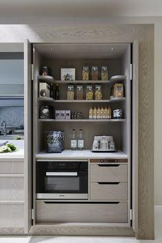 an open cabinet with food and drinks on the shelves in front of a kitchen counter