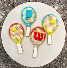 three tennis racquet shaped cookies sitting on top of a white plate