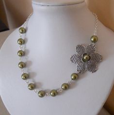 A delicate, sophisticated, elegant look to this stunning necklace.  Flowers, flowers, flowers...this necklace is a cascade of flowers. A beautiful Silver plated flower been adorned with a silver plated flower and a  olivine glass pearl. This special cascade of flowers is continued with 8 mm olivine pearls.  I used silver plated chain for this necklace and it is 18'' long with a 2'' extender.  Please email me if you need this necklace in a different size or different color of pearls (info@handcraftedjewelryart.com)  You will get the necklace in a beautiful gift box. Elegant Pearl Chain Flower Necklace, Elegant Flower Necklace With Pearl Chain, Elegant Flower-shaped Pearl Chain Necklace, Green Flower Pendant Jewelry For Wedding, Elegant Green Flower Necklace As Gift, Elegant Green Flower Necklace For Gifts, Green Flower Pendant Necklace For Wedding, Elegant Green Jewelry With Flower Decoration, Delicate Green Necklace For Wedding