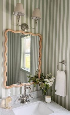 a bathroom sink sitting under a mirror in front of a wall mounted faucet