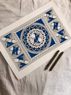 a blue and white drawing on paper with two pens