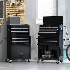 two black tool chests sitting next to each other in a room with tools on the wall