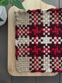 a red and white rug sitting on top of a wooden table next to a potted plant