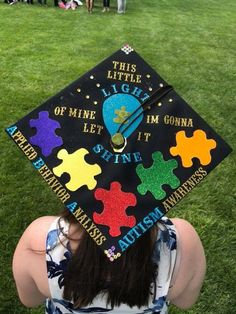 a woman wearing a graduation cap with puzzle pieces on it's back and the words, this little light of mine let't get you down